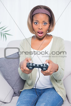 Shocked woman sitting on sofa playing video games