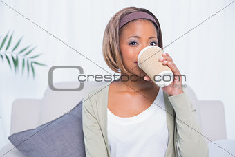 Pretty woman sitting on sofa and drinking coffee