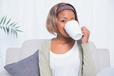 Attractive woman sitting on sofa drinking coffee
