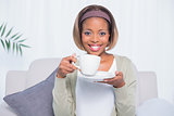 Smiling woman sitting on sofa holding coffee