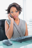 Serious businesswoman calling on phone while looking at camera