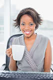 Smiling businesswoman holding cup of coffee and smiling at camera