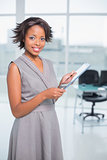 Attractive businesswoman standin in her office holding tablet