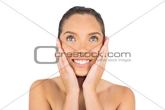 Smiling woman touching her face and looking upwards