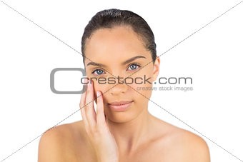 Beautiful woman touching her cheek and looking at camera