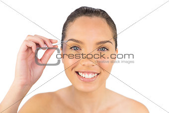 Smiling woman using her tweezers