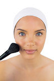 Pretty woman wearing headband using powder brush