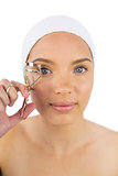 Attractive woman with headband using eyelash curler