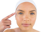 Pretty woman wearing headband putting cream on her face