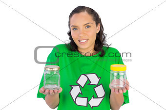 Wondering woman wearing green shirt with recycling sign holding two glass jars