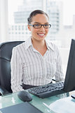 Stylish businesswoman sitting on her desk and looking at camera