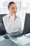 Thoughtful attractive businesswoman looking at computer screen