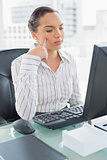 Pretty thoughtful businesswoman sitting at her desk