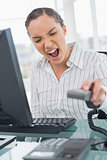 Angry businesswoman screaming while hanging up the telephone