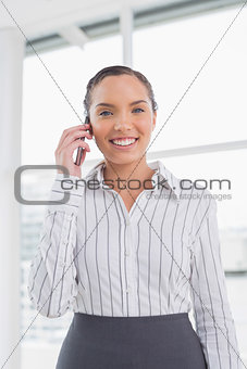 Smiling businesswoman standing in her office and talking on phone