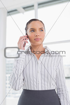 Serious businesswoman standing while talking on phone