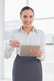 Businesswoman standing in her office and pointing at tablet screen