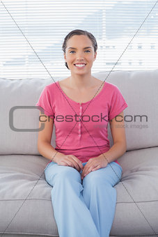 Happy woman sitting on couch and looking at camera
