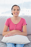 Smiling woman sitting on the sofa with a pillow