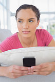 Thoughtful woman lying on sofa and texting