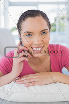 Smiling woman lying on sofa and talking on phone