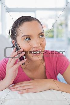Relaxed woman lying on sofa and talking on phone