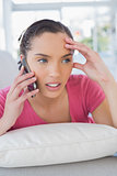 Annoyed woman lying on sofa and calling on phone