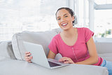 Portrait of smiling woman using laptop on sofa