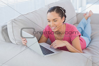 Happy woman using laptop on sofa