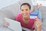 Smiling woman holding laptop showing credit card