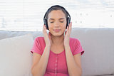 Peaceful woman relaxing on sofa with headphones on