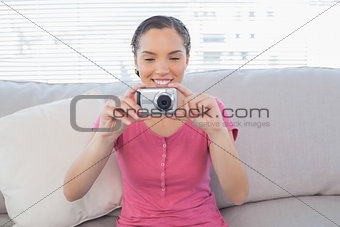 Happy woman sitting on her sofa taking a picture