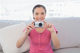 Smiling woman sitting on sofa taking a picture