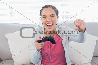 Woman playing video games on sofa and winning
