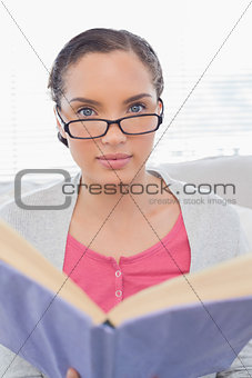 Serious woman with reading glasses holding a book