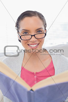 Smiling woman with reading glasses holding a book