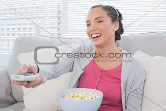 Cheerful attractive woman eating popcorn while watching tv