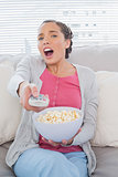 Astonished attractive woman eating popcorn while watching tv
