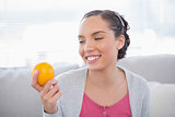 Happy woman holding orange and looking on it