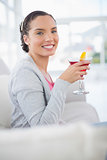 Happy woman sitting on sofa and holding cocktail