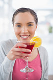 Smiling woman sitting on sofa and drinking cocktail