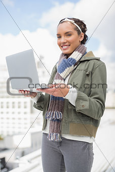 Happy woman standing outside and holding laptop