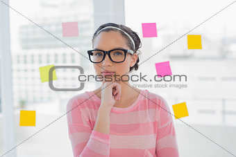 Thoughtful woman with glasses in creative office