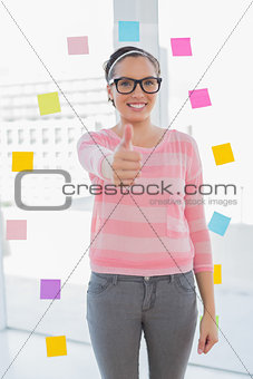 Smiling woman standing in her creative office giving thumb up