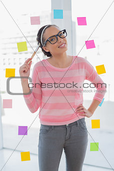 Attractive artist pointing with a brush on her head and looking at camera