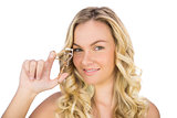 Smiling curly haired blonde holding eyelash curler