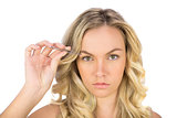 Serious curly haired blonde using tweezers