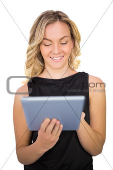Smiling gorgeous blonde in black dress using tablet