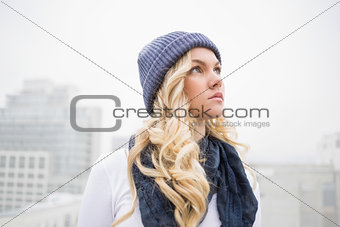 Pensive blonde in winter clothes posing outdoors