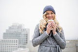 Smiling pretty blonde holding coffee outdoors